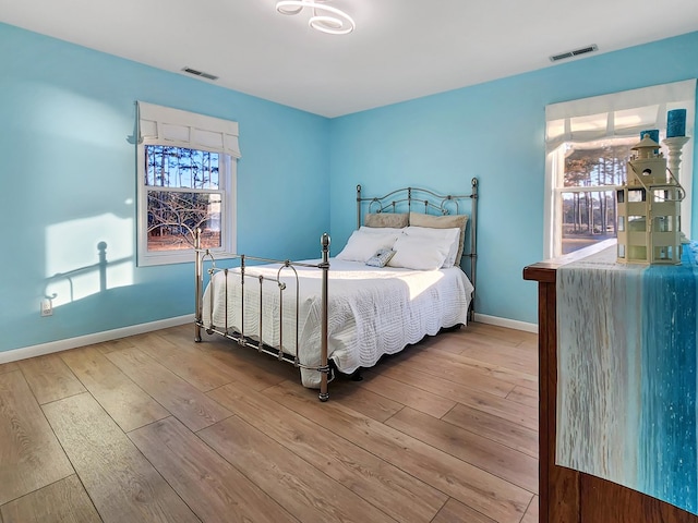 bedroom featuring visible vents, baseboards, and wood finished floors