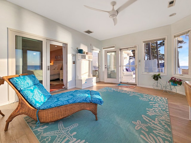 sitting room featuring baseboards, ceiling fan, visible vents, and wood finished floors