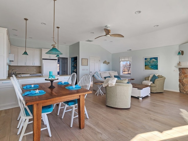 dining space with light wood-type flooring, ceiling fan, and lofted ceiling