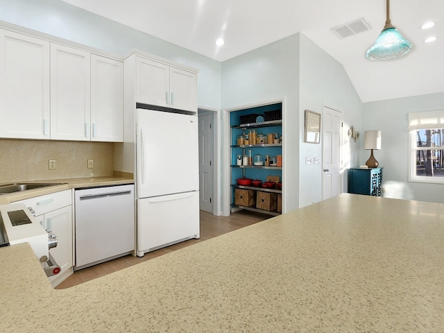 kitchen featuring white appliances, visible vents, vaulted ceiling, light countertops, and white cabinetry