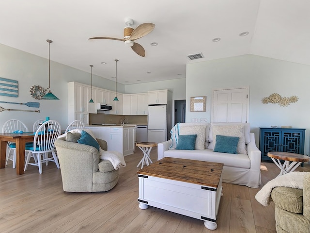 living room with lofted ceiling, light wood-style flooring, visible vents, and a ceiling fan