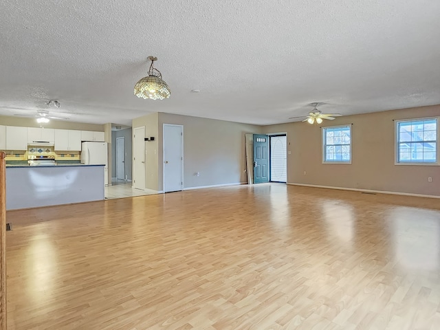 unfurnished living room with ceiling fan, light hardwood / wood-style floors, and a textured ceiling