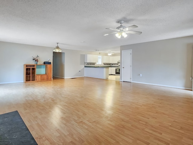 unfurnished living room featuring ceiling fan, a textured ceiling, and light hardwood / wood-style flooring