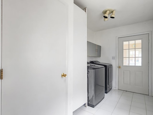 laundry area featuring washer and dryer, light tile patterned flooring, and cabinets