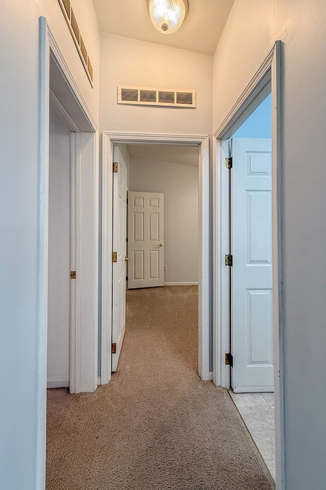 hallway featuring light colored carpet and visible vents