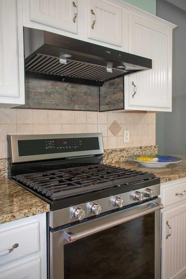 kitchen featuring white cabinets, stone countertops, gas range, and under cabinet range hood