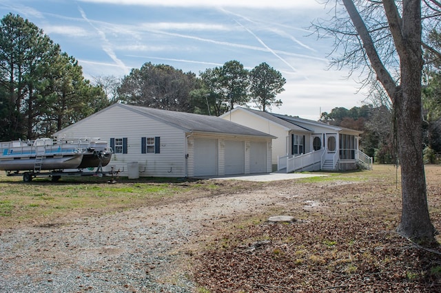 view of property exterior featuring an attached garage, a sunroom, and driveway