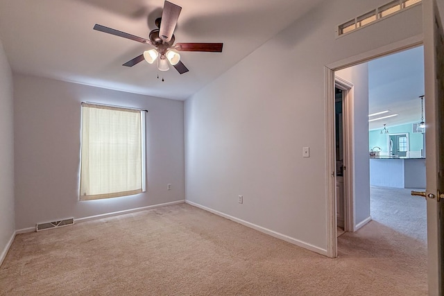 unfurnished room with visible vents, ceiling fan, light carpet, and baseboards