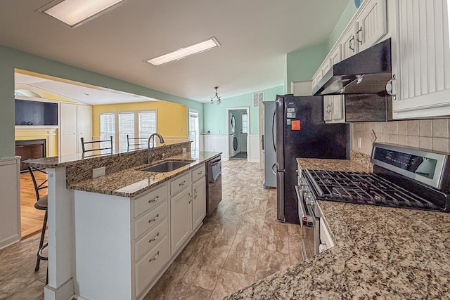 kitchen featuring a breakfast bar, white cabinets, a sink, gas range, and under cabinet range hood