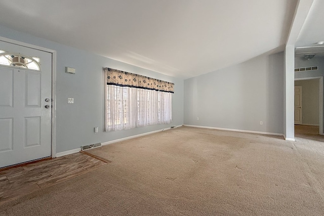 carpeted foyer entrance featuring baseboards, visible vents, and vaulted ceiling