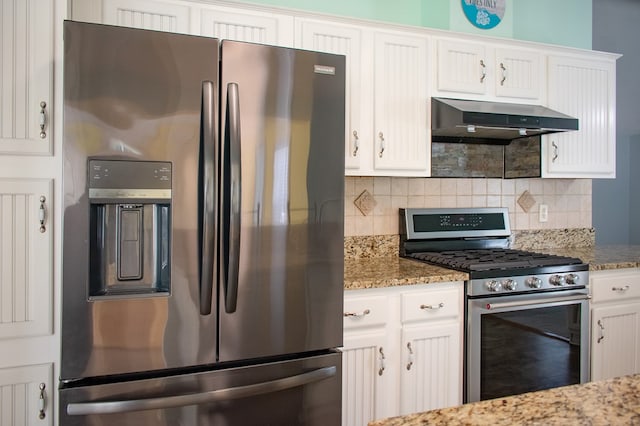 kitchen with stainless steel appliances, backsplash, white cabinetry, wall chimney range hood, and light stone countertops