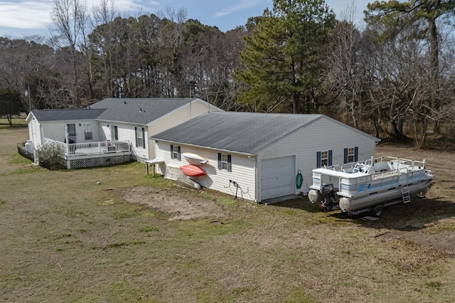 rear view of property featuring dirt driveway, a lawn, a view of trees, a deck, and a garage