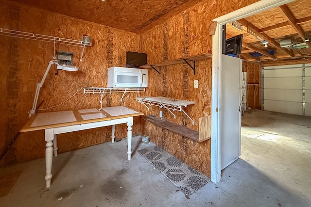 misc room with a garage and unfinished concrete flooring