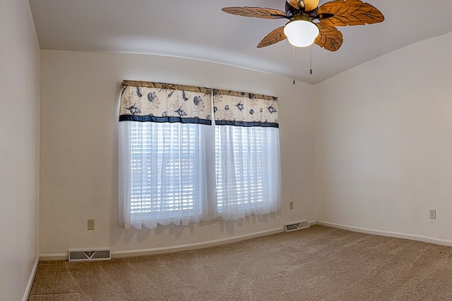 carpeted spare room with baseboards, visible vents, and a ceiling fan