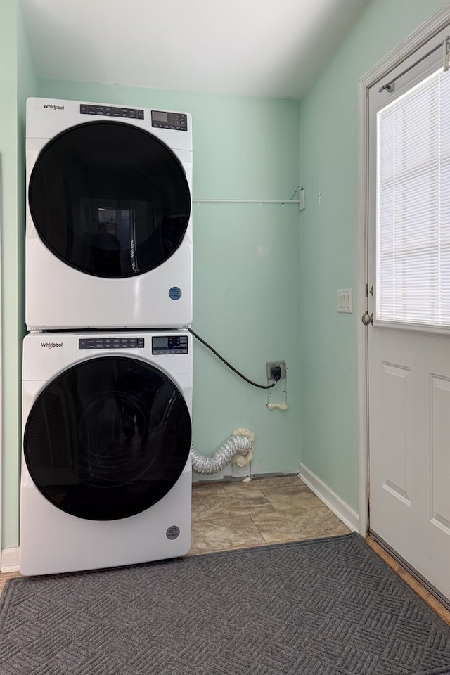 laundry area with stacked washing maching and dryer, laundry area, and dark colored carpet