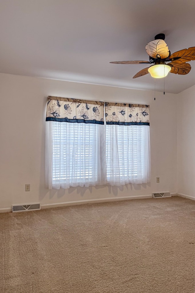 carpeted empty room with ceiling fan, visible vents, and baseboards