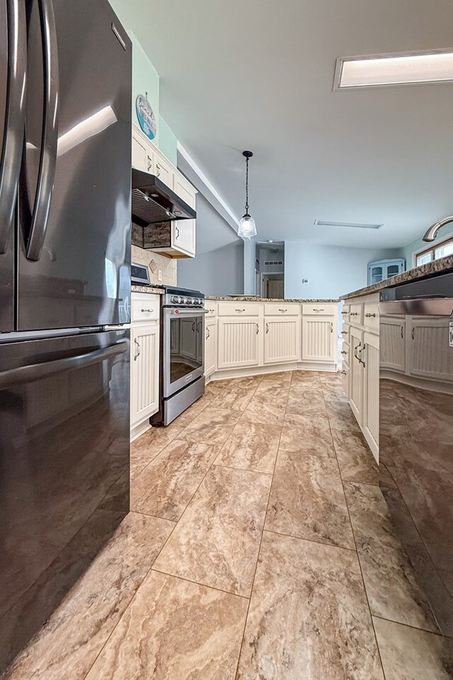 kitchen with under cabinet range hood, white cabinetry, hanging light fixtures, freestanding refrigerator, and gas stove