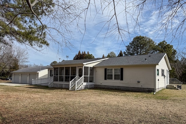 back of house with an attached garage, a sunroom, and a yard