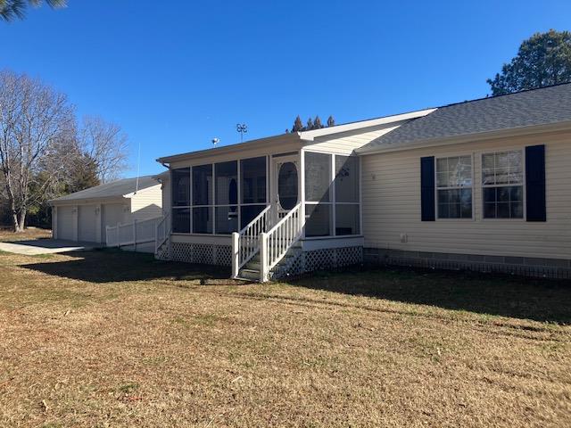 rear view of house with a garage, a sunroom, a lawn, and entry steps