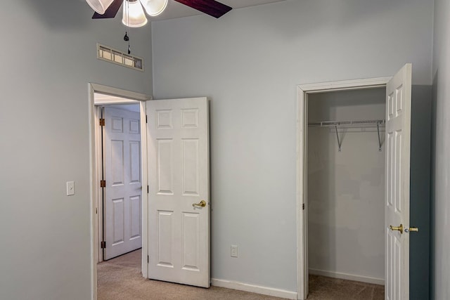 unfurnished bedroom with a closet, light colored carpet, and baseboards