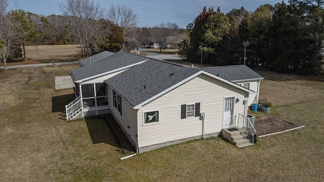 rear view of property with central air condition unit, a sunroom, a yard, and roof with shingles