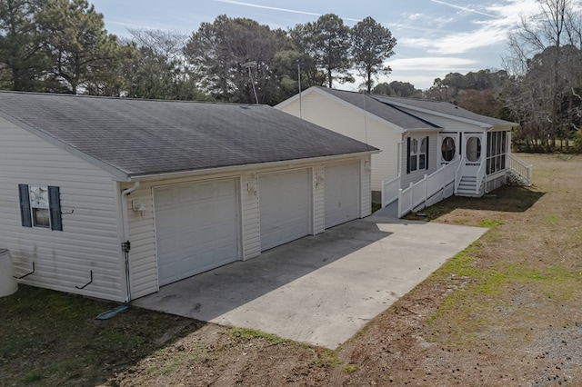 exterior space featuring a shingled roof and a detached garage