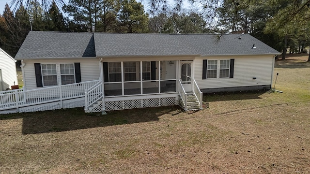 ranch-style house with entry steps, a sunroom, roof with shingles, and a front yard