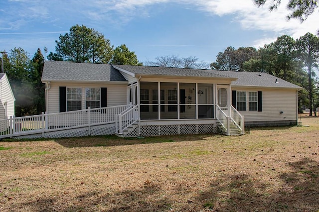 ranch-style home featuring a sunroom, roof with shingles, and a front yard