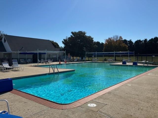 community pool with fence and a patio