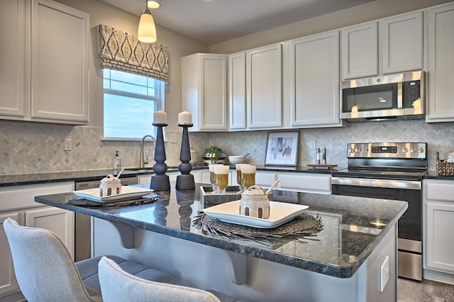 kitchen featuring a kitchen breakfast bar, white cabinetry, hanging light fixtures, and appliances with stainless steel finishes