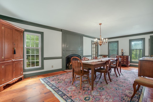 dining space with a chandelier, crown molding, and light hardwood / wood-style flooring