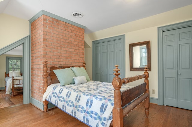 bedroom with two closets and hardwood / wood-style flooring