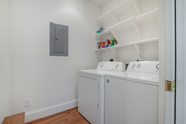 laundry room with washing machine and clothes dryer, electric panel, and light hardwood / wood-style flooring