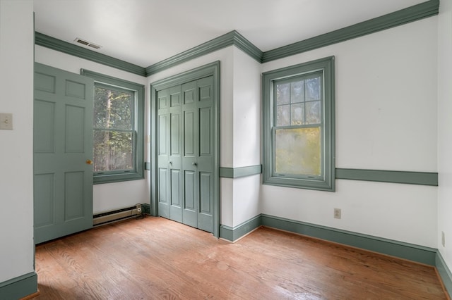 entryway with hardwood / wood-style floors, ornamental molding, and a baseboard radiator