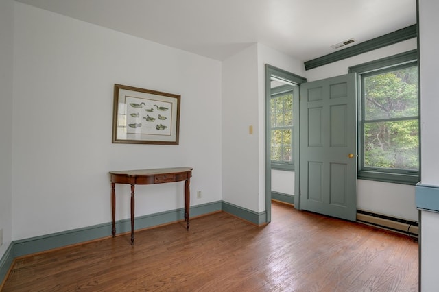 foyer entrance with wood-type flooring and a baseboard heating unit