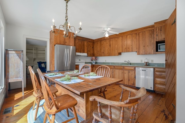 kitchen featuring ceiling fan with notable chandelier, sink, appliances with stainless steel finishes, and light hardwood / wood-style flooring