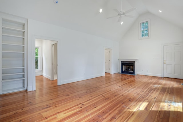 unfurnished living room with built in shelves, plenty of natural light, and light wood-type flooring