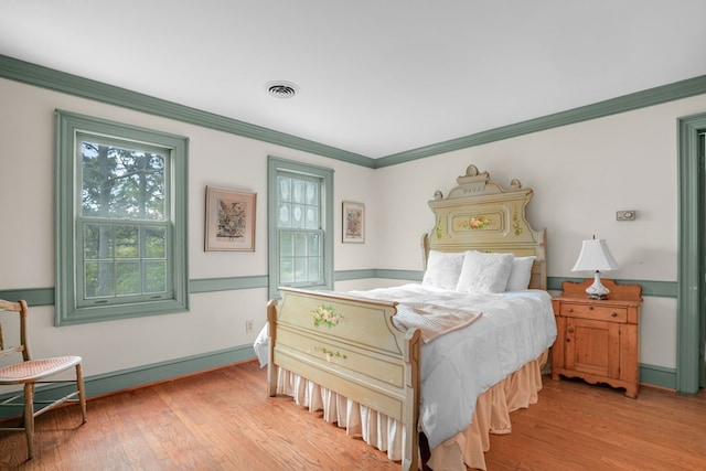 bedroom featuring ornamental molding and light wood-type flooring