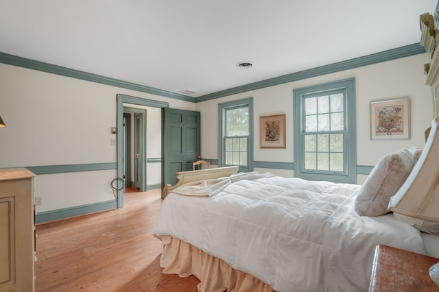 bedroom with light hardwood / wood-style floors and crown molding