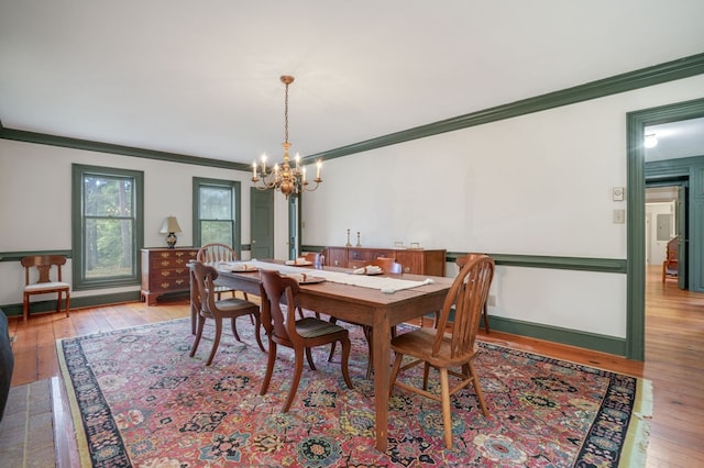 dining area featuring ornamental molding, a notable chandelier, and hardwood / wood-style flooring