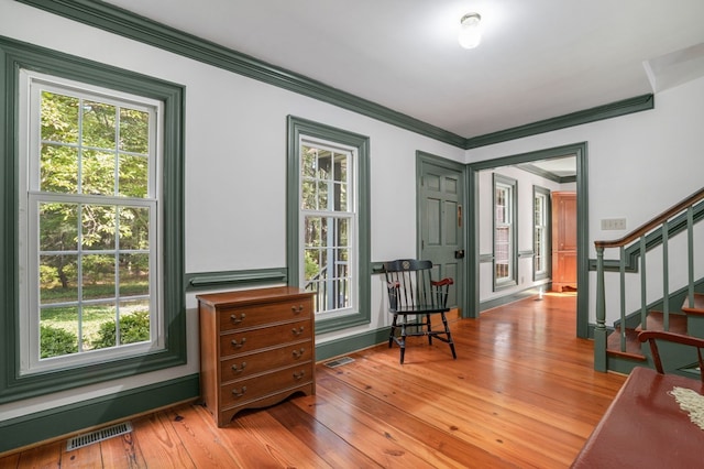 sitting room with light hardwood / wood-style floors, ornamental molding, and a wealth of natural light