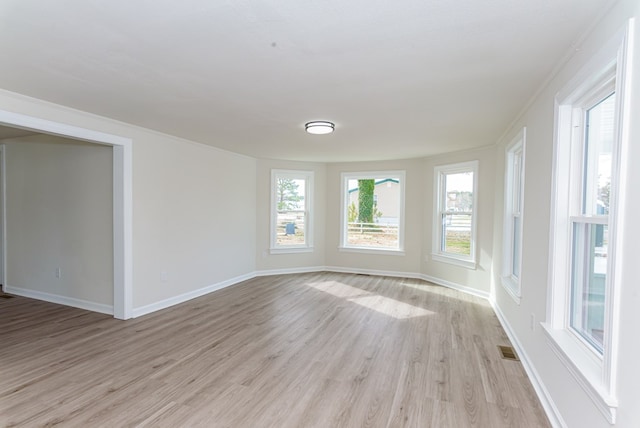 empty room with crown molding and light hardwood / wood-style flooring