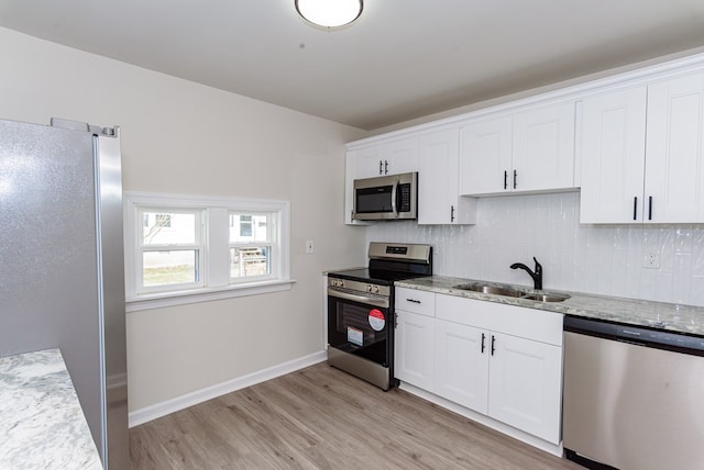 kitchen with light stone counters, appliances with stainless steel finishes, sink, and white cabinets