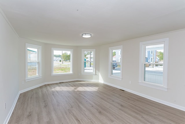 empty room featuring ornamental molding and light hardwood / wood-style flooring