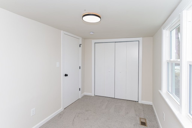 unfurnished bedroom featuring light colored carpet and a closet