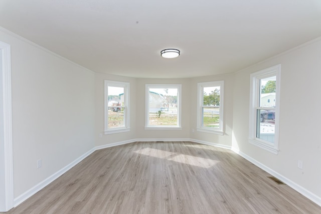 empty room with ornamental molding and light hardwood / wood-style flooring