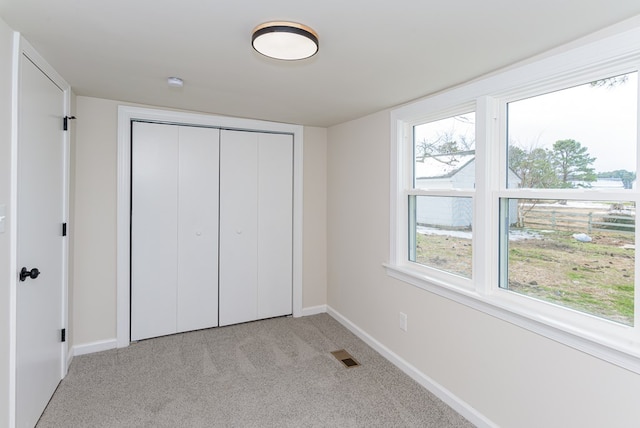 unfurnished bedroom with light colored carpet and a closet