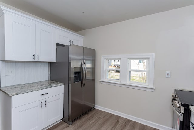 kitchen featuring stainless steel appliances, light stone countertops, light hardwood / wood-style flooring, and white cabinets