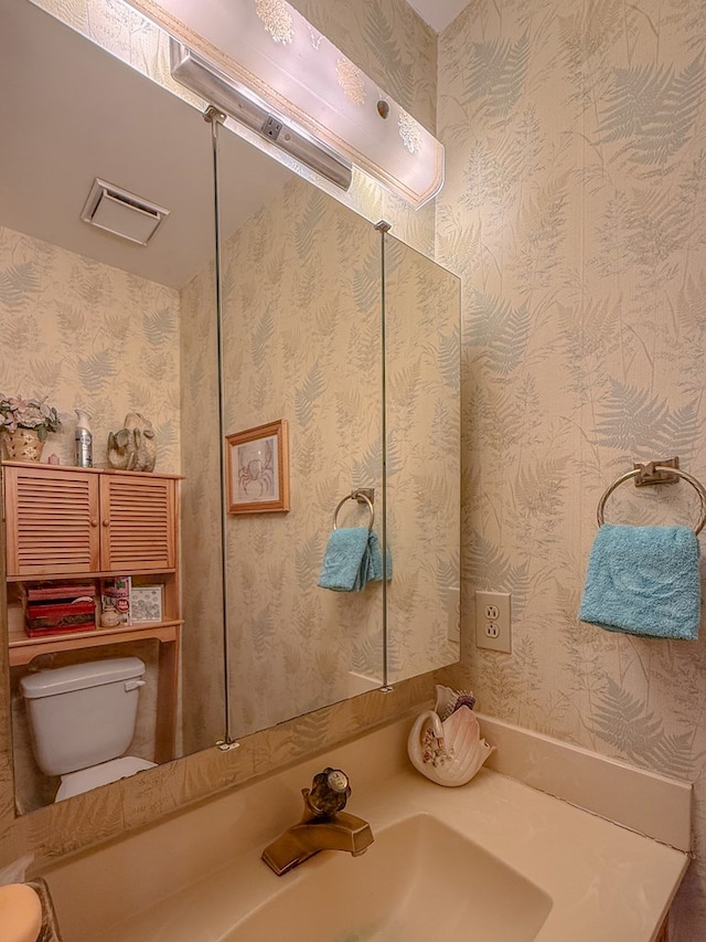 bathroom with toilet, visible vents, and a sink