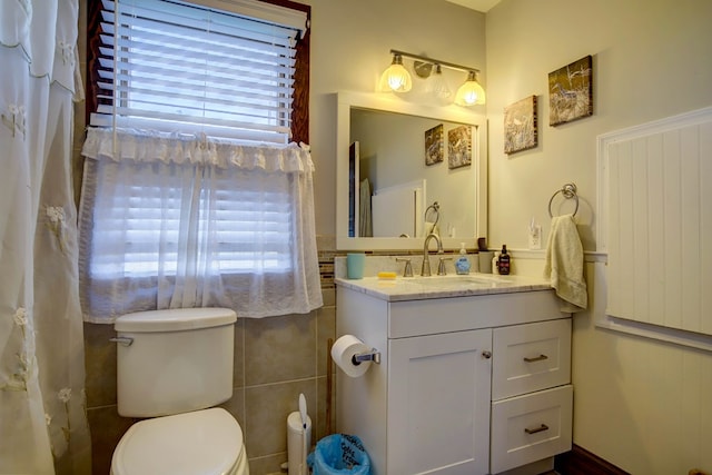 bathroom with vanity, toilet, and tile walls